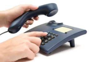 Two hands holding onto a landline phone 